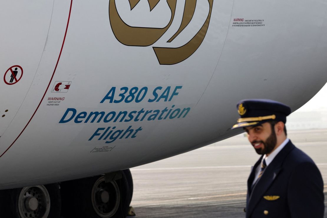 A crew member stands next to an Emirates Airbus A 380-800 aircraft, powering one of its engines with a hundred per cent Sustainable Aviation Fuel (SAF), before a demonstration flight at the Dubai International Airport in Dubai, on November 22, 2023. (Photo by Giuseppe CACACE / AFP) (Photo by GIUSEPPE CACACE/AFP via Getty Images)