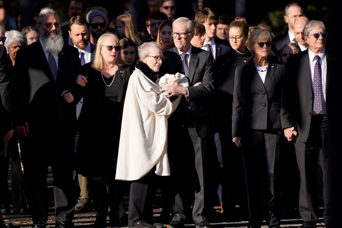 Members of the Carter family watch as Rosalynn's casket arrives at the Jimmy Carter Presidential Library and Museum on Monday. On the left, wearing the necklace, is Amy Carter, the daughter of Jimmy and Rosalynn Carter. On the right are a couple of the Carters' sons: Jack, center, and Chip, far right. Their other son, Jeff, is not pictured, but he was also there.