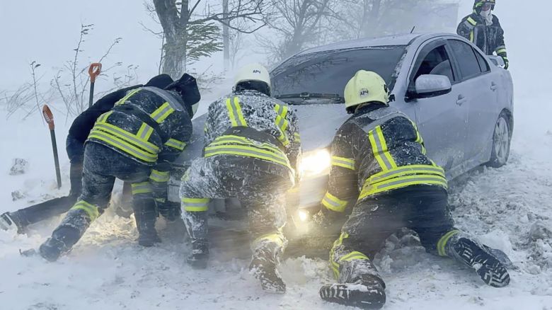 In this photo provided by the Ukrainian Emergency Service, Ukrainian Emergency workers try to push a car trapped in snow on the Odesa region highway, Ukraine, Monday, Nov. 27, 2023. Heavy snowfalls and storm has hit Ukraine on Monday leaving more than 2,000 towns and villages in war-torn country without power. (Ukrainian Emergency Service via AP Photo)