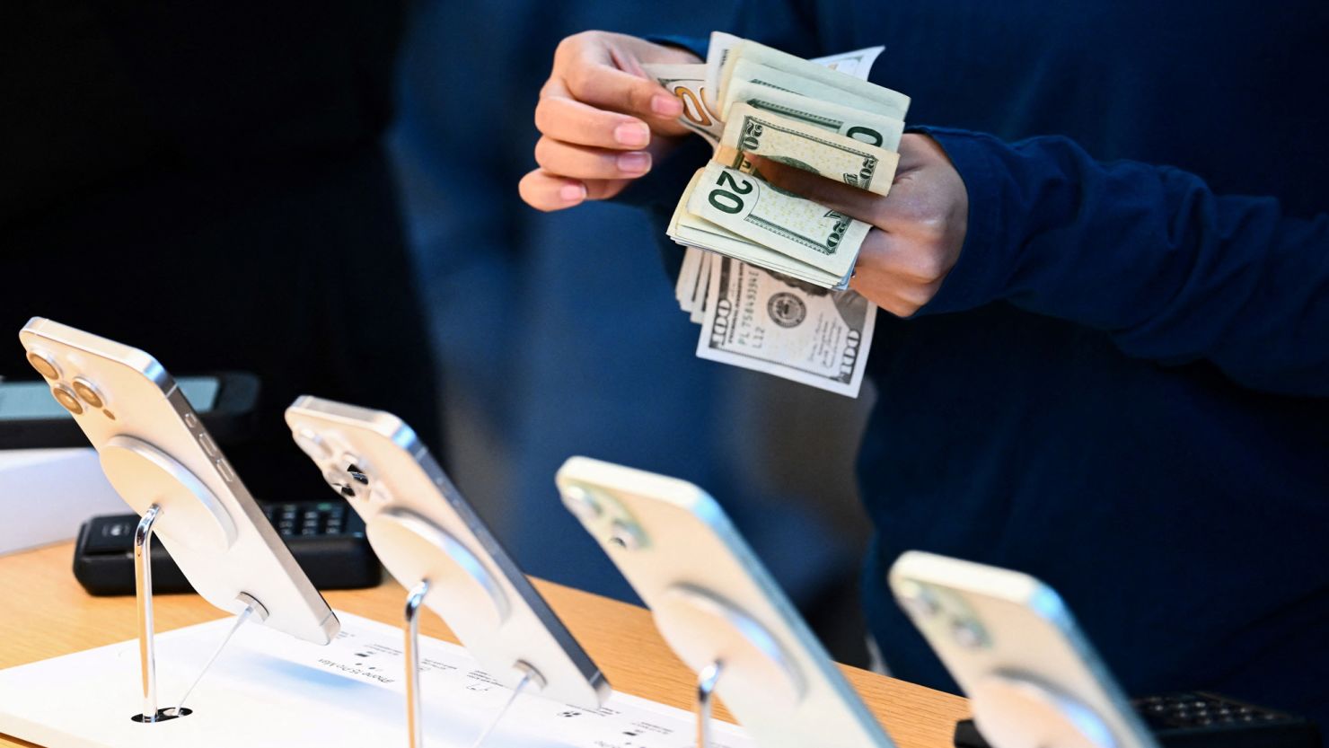 An employee counts US dollar currency as a customer pays cash for an Apple iPhone 15 series phone for sale at The Grove Apple retail store on release day in Los Angeles, California, on September 22, 2023. (Photo by Patrick T. Fallon / AFP) (Photo by PATRICK T. FALLON/AFP via Getty Images)