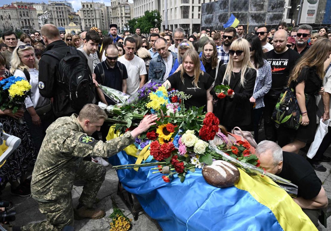 Mourners pay their respects next to the coffin of killed Ukrainian serviceman Roman Ratushny during a farewell ceremony in Kyiv on June 18, 2022, amid the Russian invasion of Ukraine. - Roman Ratushny was a leading figure of Ukraine's pro-European Maidan movement, an anti-corruption activist, and fought Russian forces with the Ukrainian army. Roman Ratushny, 24, died on June 9 near Izium, in the Kharkiv region, where Ukrainian forces are confronting the Russian army. (Photo by Genya SAVILOV / AFP) (Photo by GENYA SAVILOV/AFP via Getty Images)