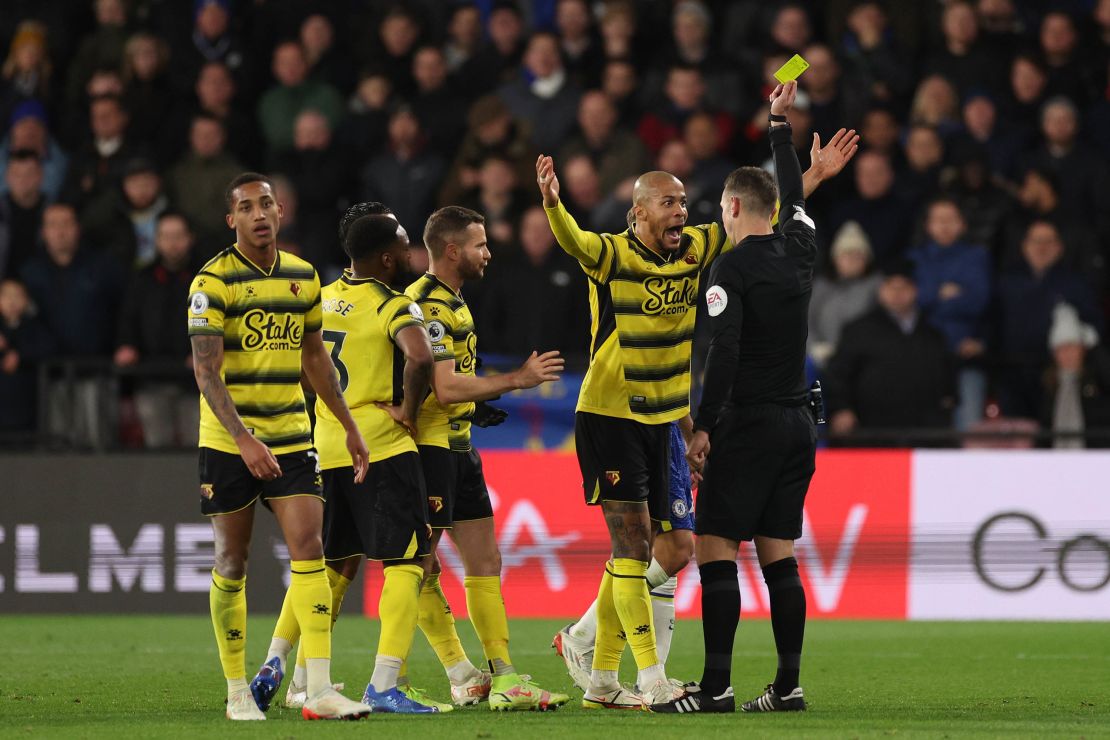 WATFORD, ENGLAND - DECEMBER 01: William Troost-Ekong of Watford FC reacts as he is shown a yellow card by referee, David Coote during the Premier League match between Watford and Chelsea at Vicarage Road on December 01, 2021 in Watford, England. (Photo by Richard Heathcote/Getty Images)