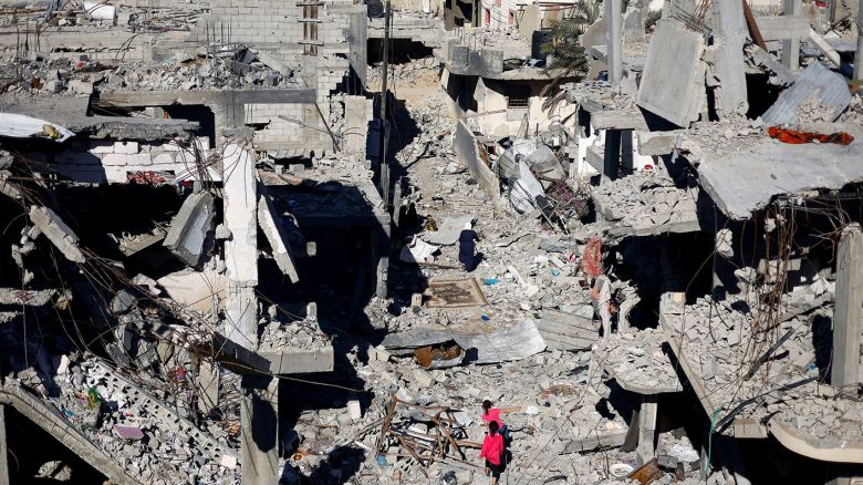 Palestinian children walk among Gaza houses destroyed in Israeli strikes during the conflict, amid the temporary truce between Israel and Hamas