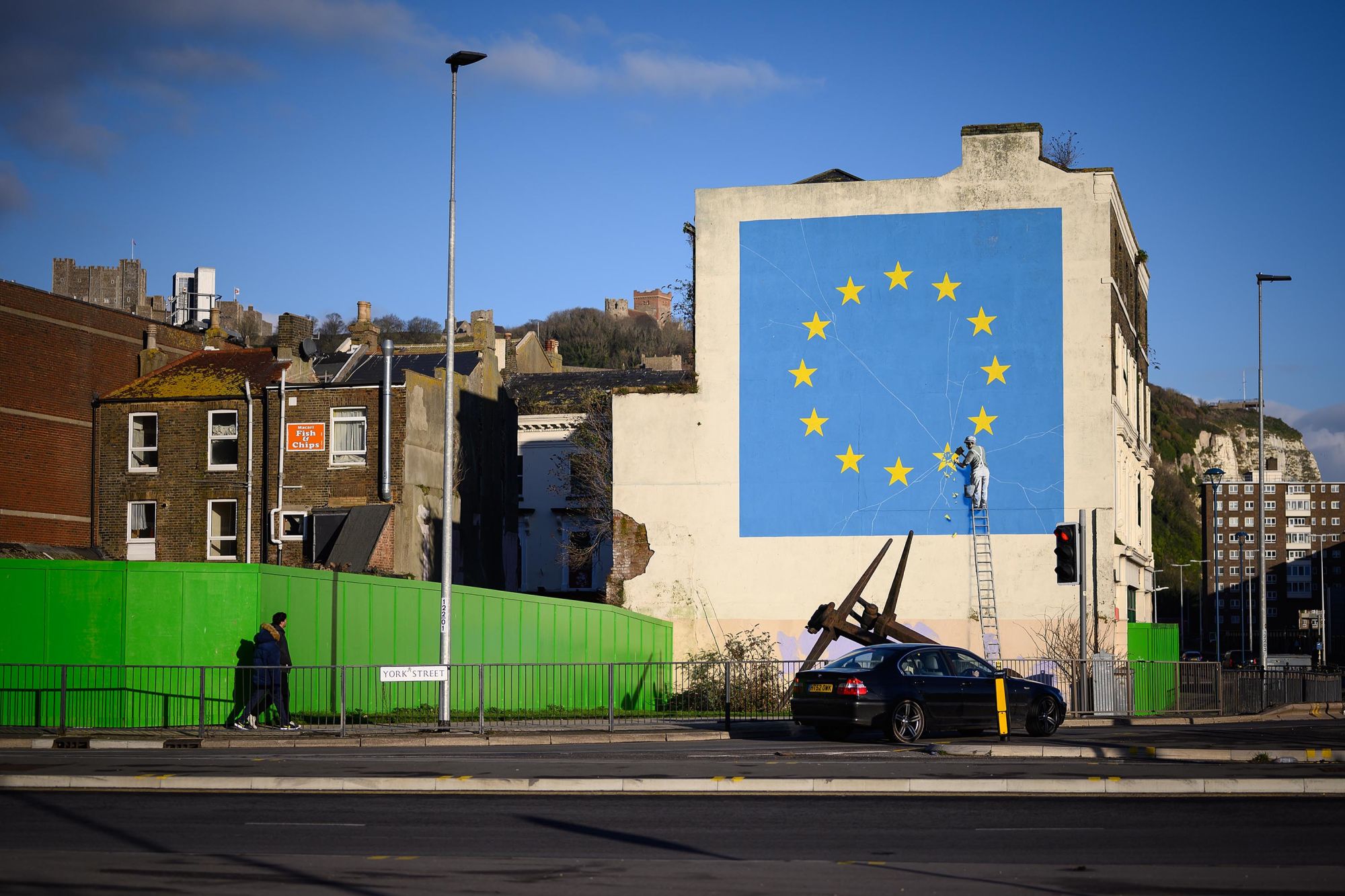 DOVER, ENGLAND - JANUARY 03: A painting depicting a workman chipping away at a star on the EU flag by artist Banksy is seen on January 03, 2019 in Dover, England. The port town of Dover, on England's south coast is the home of the famous White Cliffs, and the international gateway for the movement of passengers and trade into and from Europe. (Photo by Leon Neal/Getty Images)