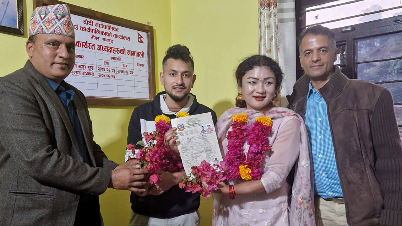 In this handout photo provided by Sunil Babu Pant, same-sex couple Surendra Pandey, second left, and Maya Gurung, who got married six years ago, pose for a photograph with their marriage registration certificate at Dorje village council office, located in the mountains west of the capital Kathmandu, Nepal, Wednesday, Nov. 29, 2023. The couple became the first in the nation to receive official same-sex marriage status. The Himalayan nation is one of the first in Asia to allow it. (Sunil Babu Pant via AP)