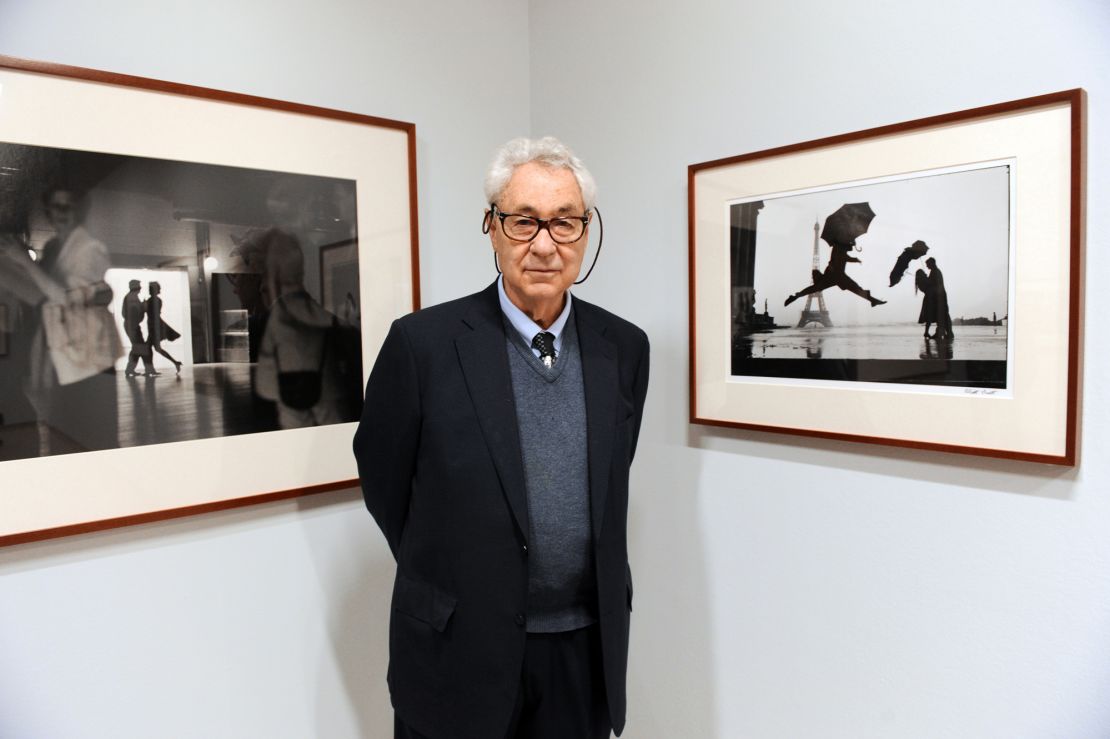 Erwitt poses with two framed examples of his work at the 2010 retrospective "Elliot Erwitt : Personal Best," presented at La Maison Europeenne de la Photographie (MEP) in Paris.