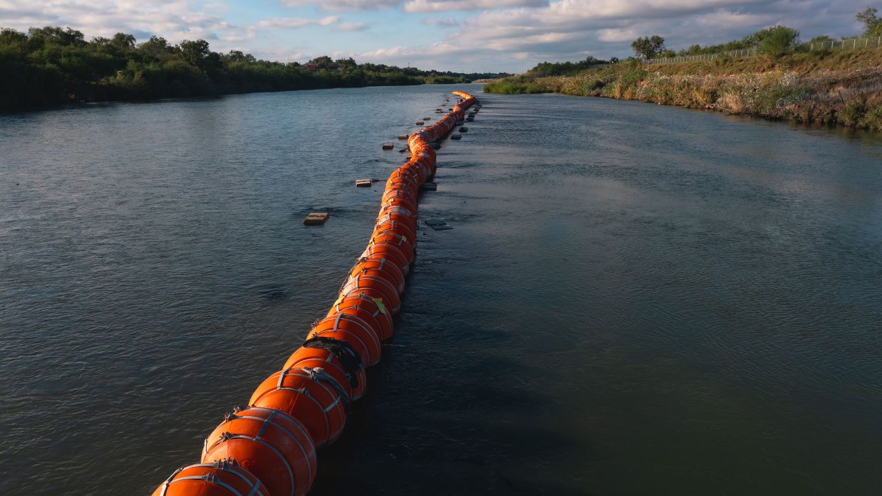 Buoys meant to deter migrant crossings is anchored in the Rio Grande River in Eagle Pass, Texas, US, on Wednesday, Oct. 11, 2023. President Biden said he sought to redirect funds to build a border wall but was unsuccessful as his administration announced plans last week to add roughly 17 miles of barriers along the Rio Grande in Texas. Photographer: Jordan Vonderhaar/Bloomberg via Getty Images