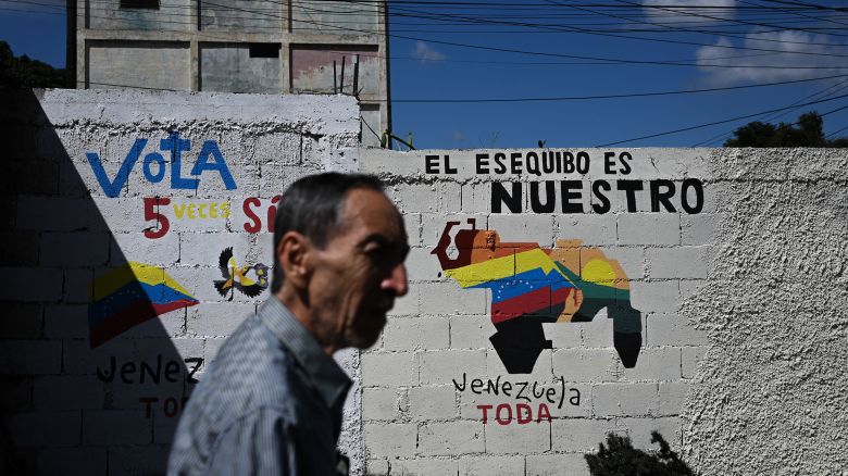 A man walks by a mural campaigning for a referendum to ask Venezuelans to consider annexing the Guyana-administered region of Essequibo, in 23 de Enero neighbourhood in Caracas on November 28, 2023. Venezuela is scheduled to hold a controversial referendum on December 3, to annex a disputed oil-rich territory administered by neighbouring Guyana. The government of Nicolas Maduro has organized the poll to ask Venezuelans to consider annexing the Essequibo region, which makes up two-thirds of tiny Guyana but is claimed by Caracas. (Photo by Federico PARRA / AFP) (Photo by FEDERICO PARRA/AFP via Getty Images)