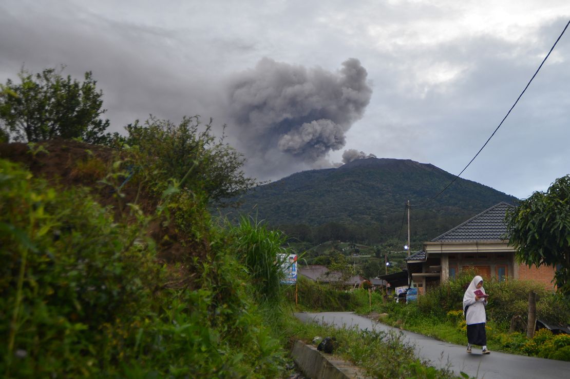 A student walks as Mount Marapi volcano spews volcanic ash as seen from Nagari Batu Palano in Agam, West Sumatra province, Indonesia, December 4, 2023.