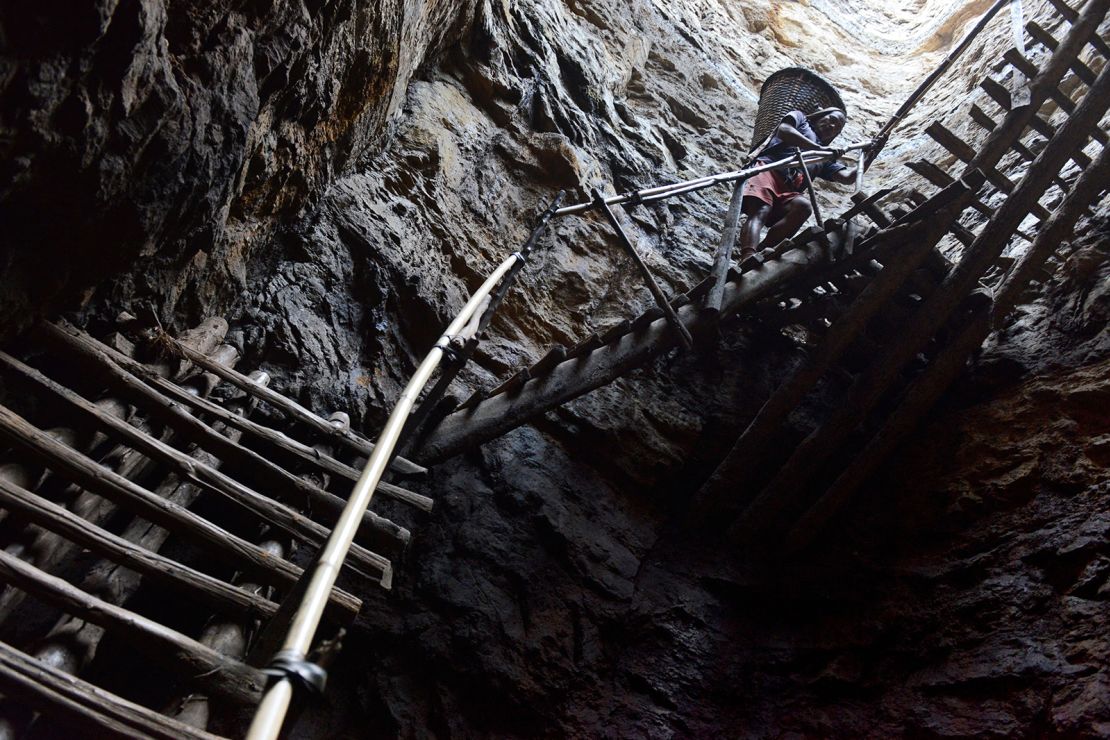 In this photograph taken on January 31, 2013, a miner slowly carries a heavy load of wet coal on a basket hundreds of feet up on wooden slats that brace the sides of a deep coal mine shaft near Rimbay village in the Indian northeastern state of Meghalaya.