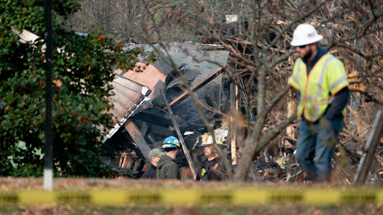 Workers look at a home that exploded in Arlington, Virginia, on December 4 and rocked a neighborhood with a powerful blast, on December 5, 2023. Three police officers received minor injuries but were not taken to hospitals, the department said. Officials are unaware of anyone else who was hurt, they said at a news conference. (Photo by Stefani Reynolds / AFP) (Photo by STEFANI REYNOLDS/AFP via Getty Images)
