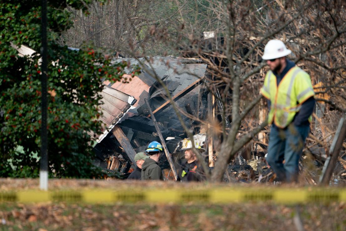 Workers look at a home that exploded in Arlington, Virginia, on December 4 and rocked a neighborhood with a powerful blast, on December 5, 2023. Three police officers received minor injuries but were not taken to hospitals, the department said. Officials are unaware of anyone else who was hurt, they said at a news conference. (Photo by Stefani Reynolds / AFP) (Photo by STEFANI REYNOLDS/AFP via Getty Images)