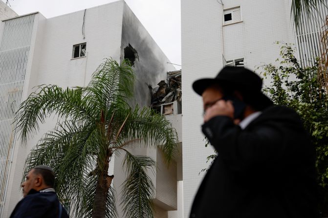 People walk past a building damaged in a rocket attack in Ashkelon, Israel, on December 5.