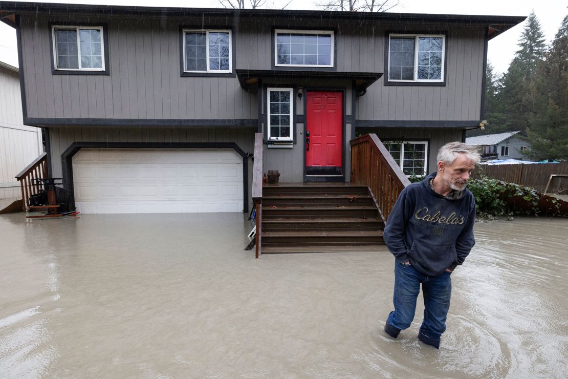Bernie Crouse wades through water outside his home after the nearby South Fork Stillaguamish River crested early in the morning flooding several houses in this neighborhood, Dec. 5, 2023,  in the Arlington area of Seattle, Washington. Crouse got his dog Max out of the basement as it began flooding, after getting a call from another neighbor. (Ken Lambert/The Seattle Times via AP)