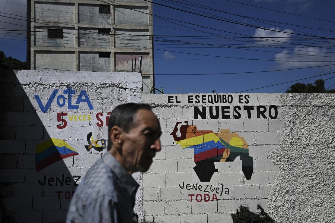 A man walks by a mural campaigning for a referendum to ask Venezuelans to consider annexing the Guyana-administered region of Essequibo, in 23 de Enero neighbourhood in Caracas on November 28, 2023. Venezuela is scheduled to hold a controversial referendum on December 3, to annex a disputed oil-rich territory administered by neighbouring Guyana. The government of Nicolas Maduro has organized the poll to ask Venezuelans to consider annexing the Essequibo region, which makes up two-thirds of tiny Guyana but is claimed by Caracas. (Photo by Federico PARRA / AFP) (Photo by FEDERICO PARRA/AFP via Getty Images)