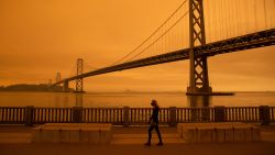 TOPSHOT - A woman walks along The Embarcadero under an orange smoke-filled sky in San Francisco, California on September 9, 2020. - More than 300,000 acres are burning across the northwestern state including 35 major wildfires, with at least five towns "substantially destroyed" and mass evacuations taking place. (Photo by Brittany Hosea-Small / AFP) (Photo by BRITTANY HOSEA-SMALL/AFP via Getty Images)