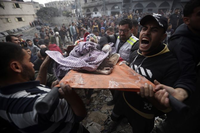 Palestinians carry a dead girl, found under the rubble of a destroyed building following Israeli airstrikes in Khan Younis, in Gaza, on December 7.