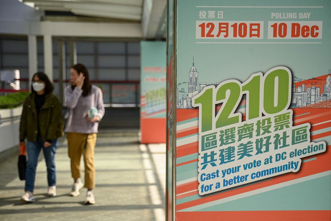 Pedestrians walk past election posters to promote the upcoming district council elections in Hong Kong on December 8, 2023.