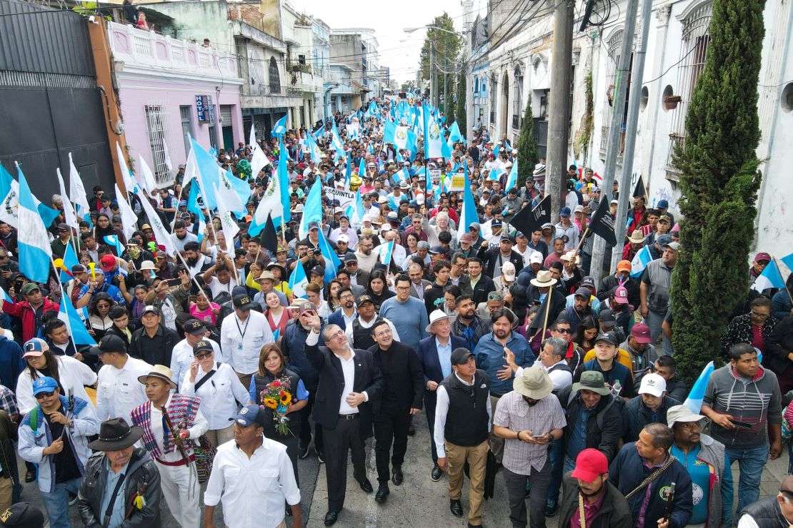 Guatemala's President-elect Bernardo Arevalo (C) waves to supporters while taking part in the "March for Democracy" to demand the resignation of Attorney General Consuelo Porras and prosecutor Rafael Curruchiche, accused of generating an electoral crisis, in Guatemala City on December 7, 2023. Attorney General since 2018, Consuelo Porras went from having a discreet judicial career to being at the center of the political tension that Guatemala is experiencing, accused of being the architect of an offensive to prevent the elected president, Bernardo Arevalo, from assuming power in January. (Photo by Carlos ALONZO / AFP) (Photo by CARLOS ALONZO/AFP via Getty Images)