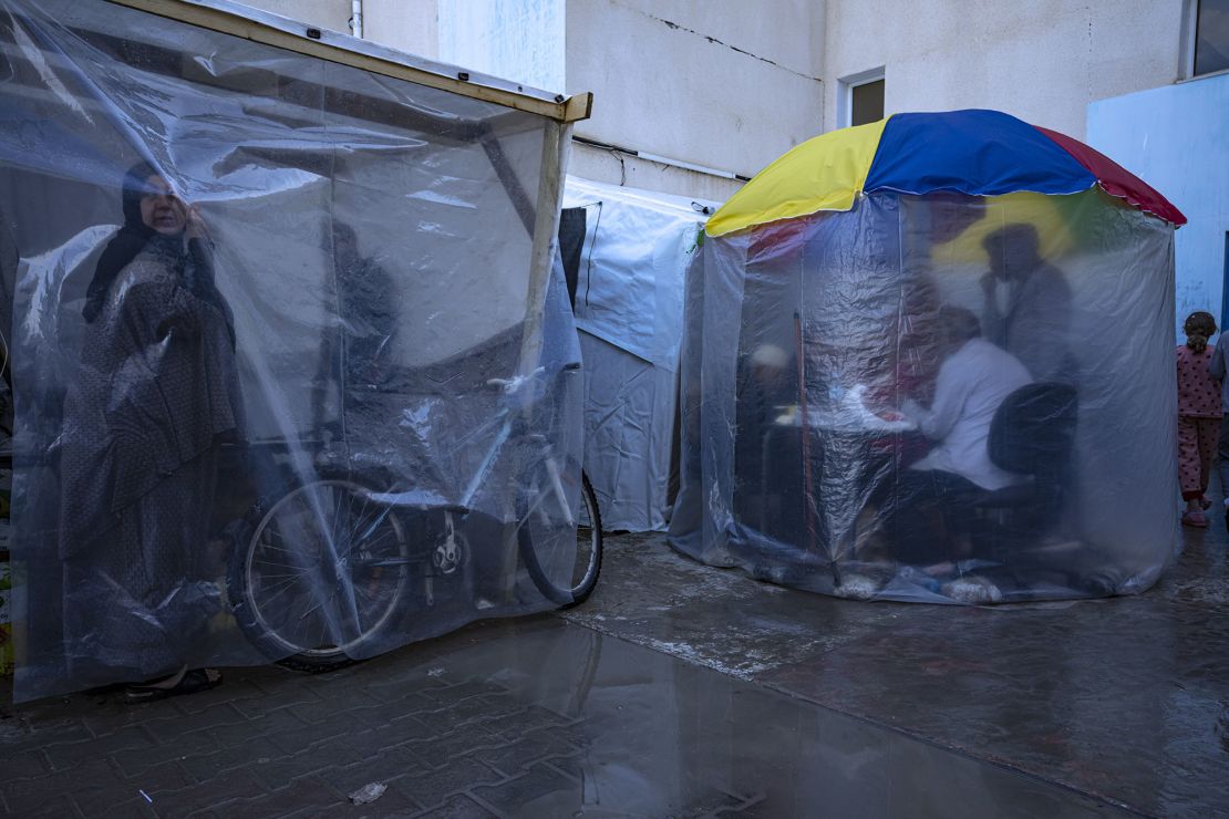 Palestinians displaced by the Israeli bombardment of the Gaza Strip seek cover from a winter rainfall at a U.N. tent camp in the southern town of Khan Younis, Gaza Strip, Sunday, Nov. 19, 2023. Hundreds of thousands of Palestinians have fled their homes in northern Gaza as Israel moves ahead with a ground offensive against the ruling Hamas militant group. (AP Photo/Fatima Shbair)