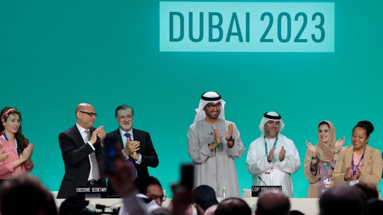 COP28 president Sultan Ahmed Al Jaber (C) applauds among other officials before a plenary session during the United Nations climate summit in Dubai on December 13, 2023. Nations adopted the first ever UN climate deal that calls for the world to transition away from fossil fuels. "We have the basis to make transformational change happen," COP28 president Sultan Al Jaber said at the UN climate summit in Dubai before the deal was adopted by consensus, prompting delegates to rise and applaud. (Photo by Giuseppe CACACE / AFP)