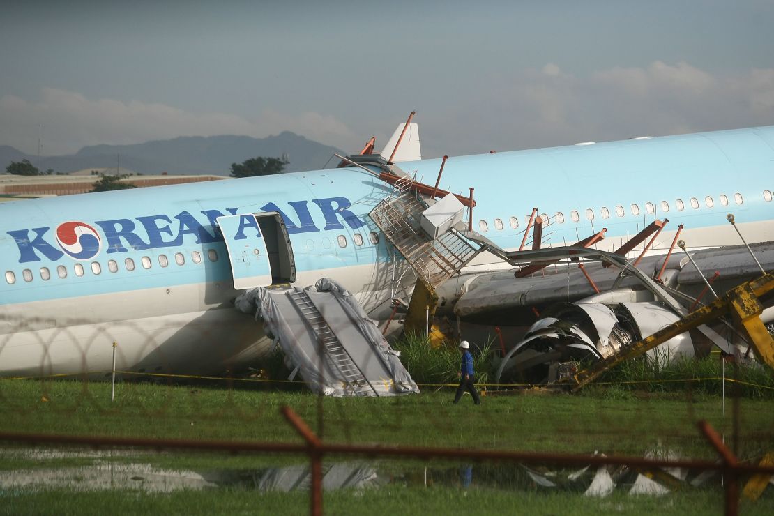 A man walks beside a damaged Korean Air plane after it overshot the runway at the Mactan-Cebu International Airport in Cebu, central Philippines early Monday Oct. 24, 2022. The Korean Air plane overshot the runway while landing in bad weather in the central Philippines late Sunday, but authorities said all 173 people on board were safe. (AP Photo/Juan Carlo De Vela)