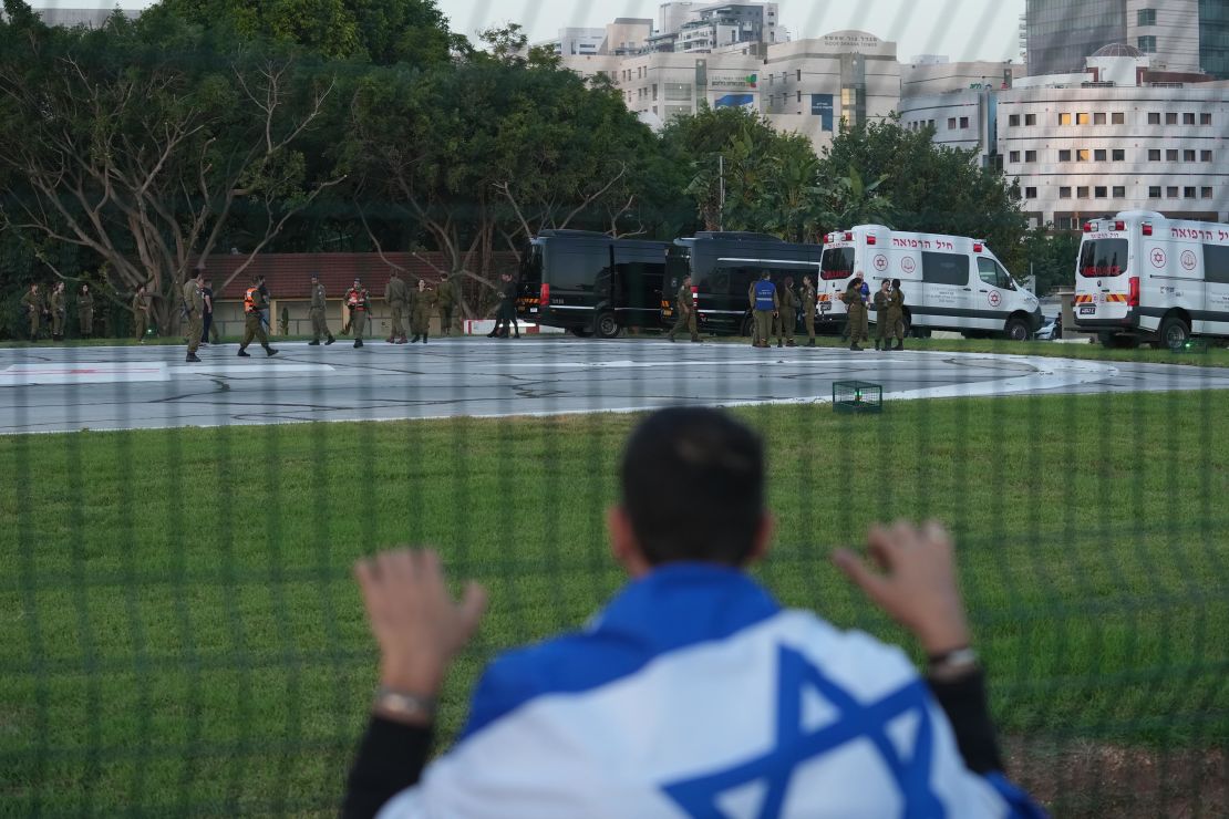 PETAH TIKVA, ISRAEL - NOVEMBER 24: A man wearing an Israeli flag looks toward ambulances outside the Schneider medical centre, where it is believed some of the released hostages may be brought, on November 24, 2023 in Petah Tikva, Israel. A four-day ceasefire began between Israel and Hamas began this morning, although Israeli forces remain in Gaza. A total of 50 hostages currently held by Hamas are to be released during a four-day truce with Israel, the first such pause in fighting since Oct. 7, when Hamas launched its surprise attack and Israeli responded with a vast military offensive to destroy the militant group that governs Gaza. Under the deal, 150 Palestinian prisoners are also to be released from Israel, and more humanitarian aid will be admitted at the Gaza-Egypt border crossing. (Photo by Erik Marmor/Getty Images)