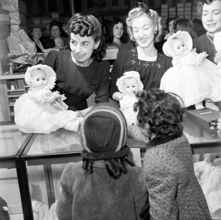 Women show dolls to children at a Macy's store around Christmas in 1942.
