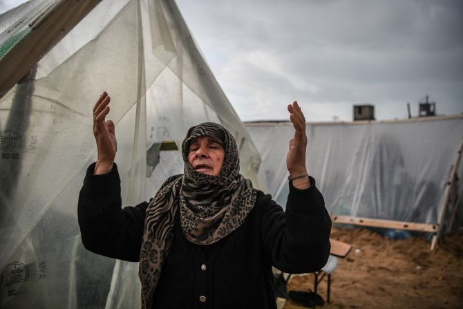 A Palestinian woman reacts as she walks past makeshift tents during a rainy day at a UN relief agency logistics base in Rafah, Gaza, on December 13.