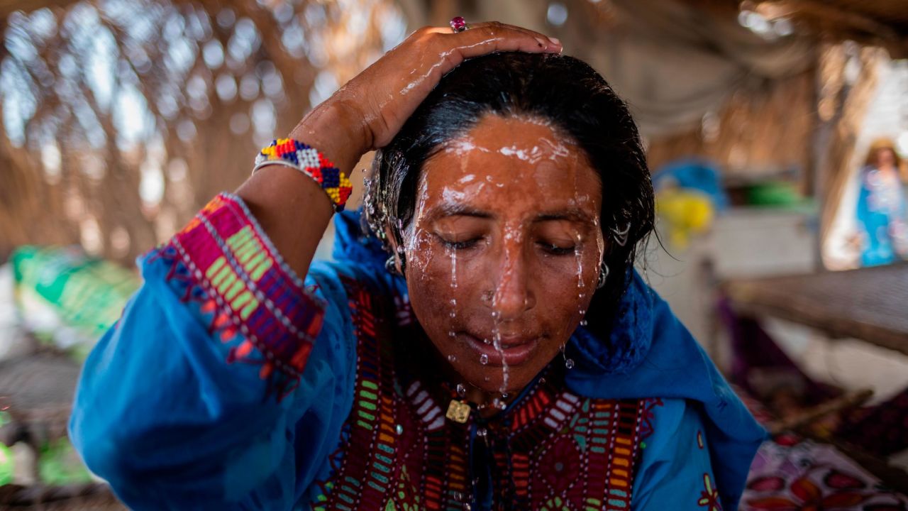 Hajani Lashari hands Qazbano Lashari a bowl of water to pour over herself. Lashari says they usually pour water on themselves a couple of times in the day due to the extreme heat. Female members in her family say that it is very important to monitor her temperature as she has entered labour on August 11, 2023 in Shikarpur, Sindh, Pakistan. Saiyna Bashir for CNN 