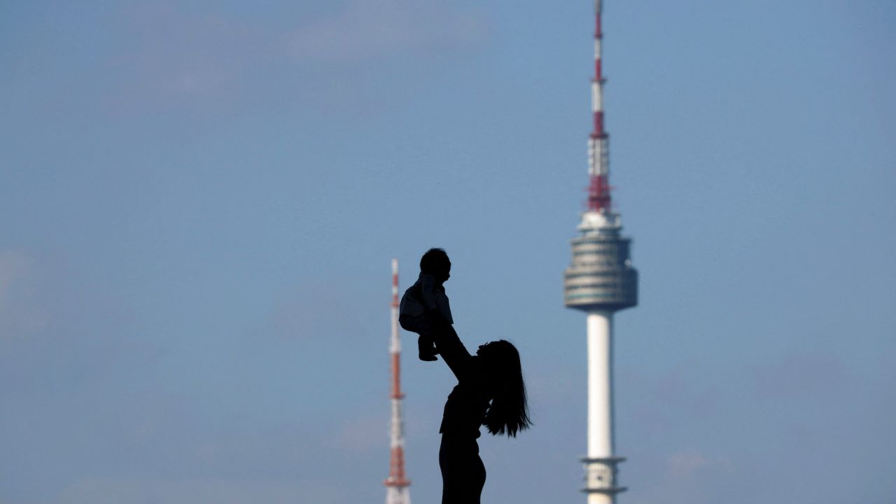 FILE PHOTO: A woman holding up her baby is silhouetted against the backdrop of N Seoul Tower, commonly known as Namsan Tower, in Seoul, South Korea, October 2, 2018.   REUTERS/Kim Hong-Ji/File Photo