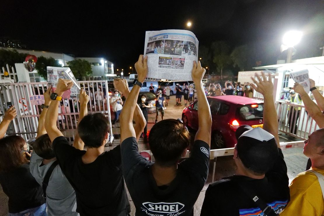 Apple Daily journalists hold aloft copies of the newspaper's last edition as the paper closed after 26 years on June 24, 2021