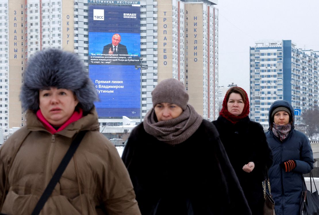 Women walk near an electronic screen on the facade of a building showing an image of Russian President Vladimir Putin and a quote from his annual end-of-year press conference and the Direct Line question and answer session, in Moscow, Russia December 14, 2023. REUTERS/Maxim Shemetov     TPX IMAGES OF THE DAY