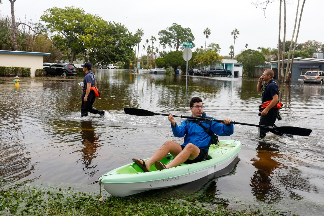 December 17, St. Petersburg, Florida, USA: Local resident Lance Kreitzer, 21, waits in his kayak, while fire and rescue workers walk down a flooded to assist residents near the intersection of 14th Lane NE and Shore Acres Boulevard on Sunday, Dec. 17, in St. Petersburg.