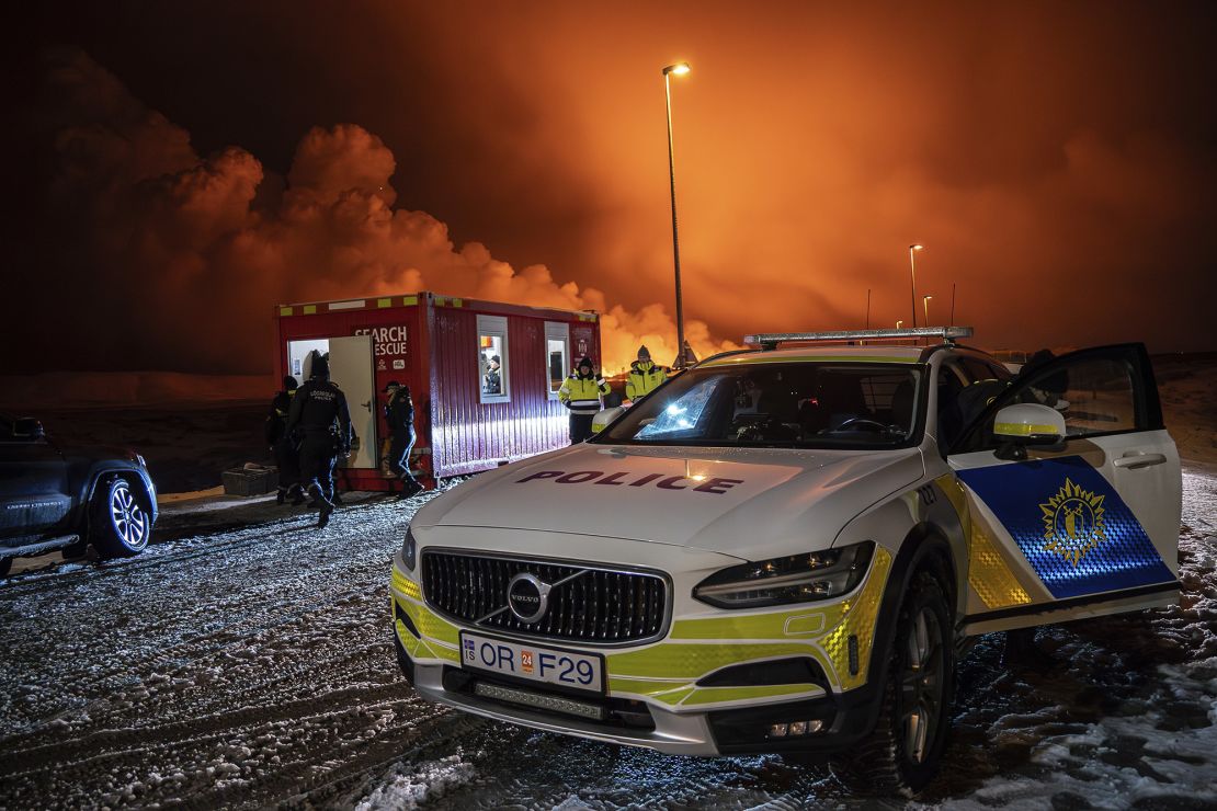 The police vehicle is parked at the entrance of the road to Grindavík with the eruption in the background, near Grindavik on Iceland's Reykjanes Peninsula, Monday, Dec. 18, 2023. A volcanic eruption started Monday night on Iceland's Reykjanes Peninsula, turning the sky orange and prompting the country's civil defense to be on high alert.  (AP Photo/Marco Di Marco)
