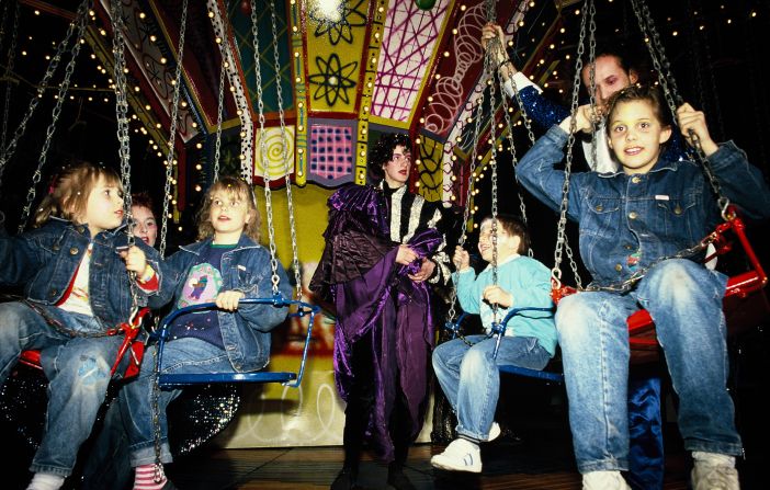 Children (and costumed performers) enjoy Kenny Scharf's painted chair swing ride.