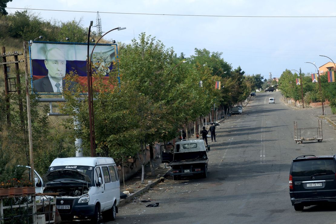 A billboard with the image of the Russian President Vladimir Putin and Armenian flags hanging from lamp posts as Azeri police patrol a road leading into the city of Stepanakert, retaken last week, during an Azeri government organized media trip, in Azerbaijan's controlled region of Nagorno-Karabakh, on October 2, 2023. After three decades of Armenian control, the separatist authorities have agreed to disarm, dissolve their government and reintegrate with Azerbaijan in the wake of Baku's one-day military operation in late September. The separatist government said president Samvel Shahramanyan will stay in Karabakh's main city of Stepanakert with a group of officials "until the search and rescue operations for the remainder of those killed and those missing" are completed. (Photo by EMMANUEL DUNAND / AFP) (Photo by EMMANUEL DUNAND/AFP via Getty Images)