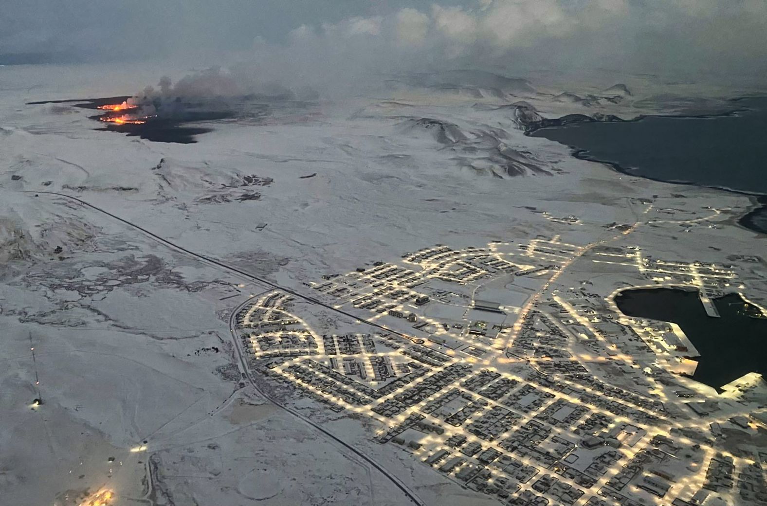 The evacuated Icelandic town of Grindavik, right, is seen as smoke billows and lava is thrown into the air during the volcanic eruption.
