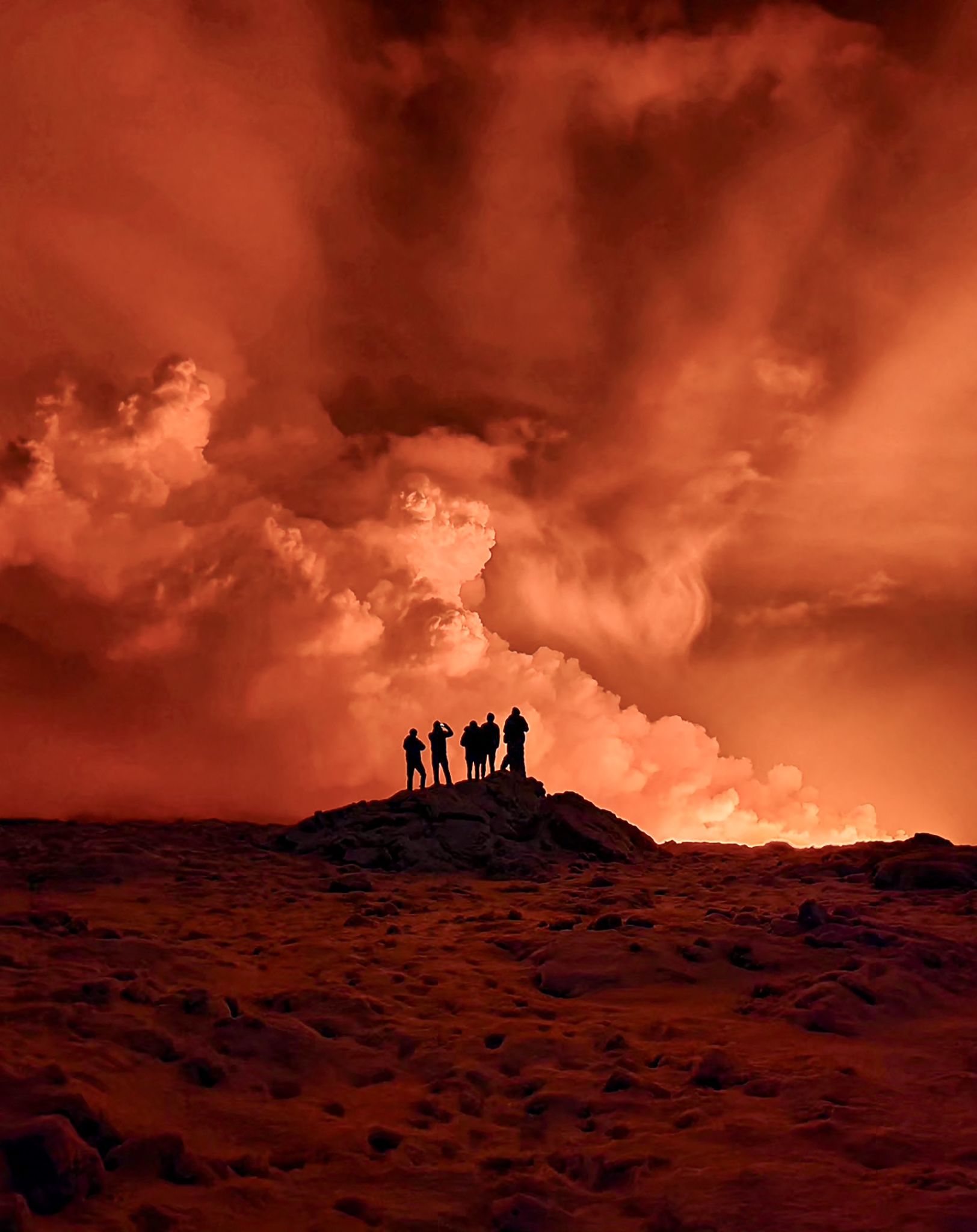 Local residents watch smoke billow as the lava colors the night sky orange on December 19.