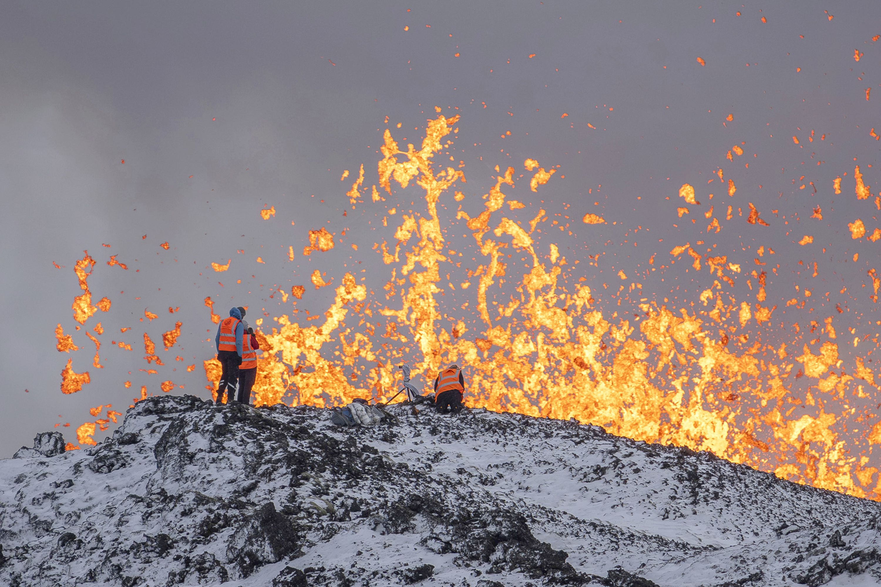 Scientists from the University of Iceland take measurements and samples while standing on the ridge of the eruptive fissure of an active volcano near Grindavik, Iceland, on Tuesday, December 19.