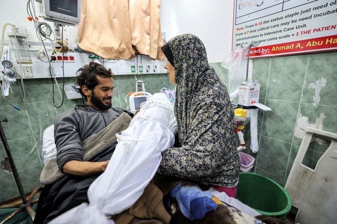 A wounded man bids farewell to the body of his son following overnight Israeli bombardments at a hospital in Rafah, Gaza, on December 19.