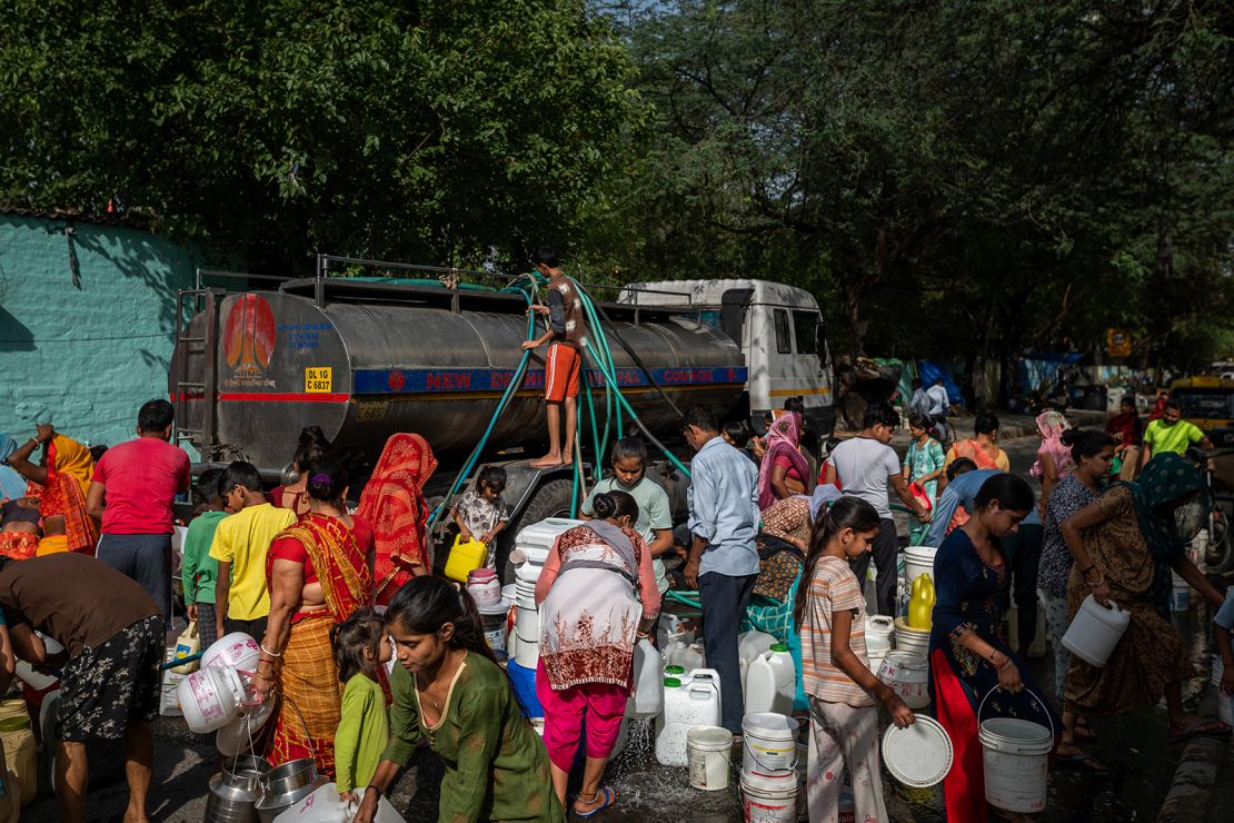 Mieszkańcy napełniają wodę ze zbiornika w slumsach w New Delhi w Indiach, piątek, 19 maja 2023 r.