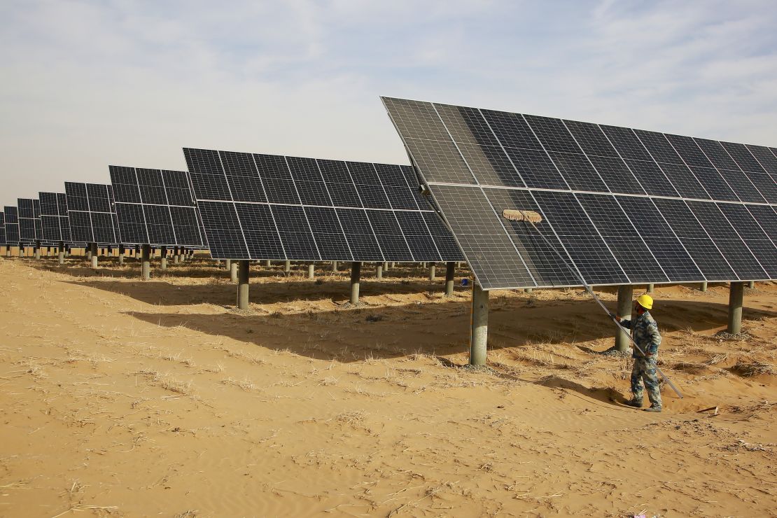 A worker cleans solar panels at a new energy base of Tengger Desert on December 9, 2023 in Zhongwei, Ningxia Hui Autonomous Region of China.