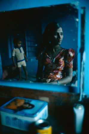 A young woman and a child seen reflected in a mirror. During the day, the women stay in their rooms, sleep, sew, play with children, cook on the floor. "It is all very much like normal Indian family life," said Mark. 