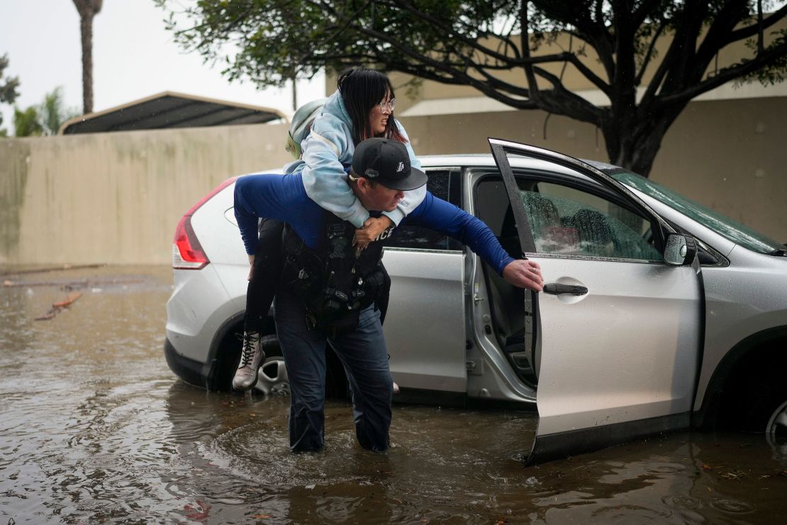 Det. Bryce Ford of the Santa Barbara, California, Police Department helps a motorist out of her car on a flooded street during a rainstorm.