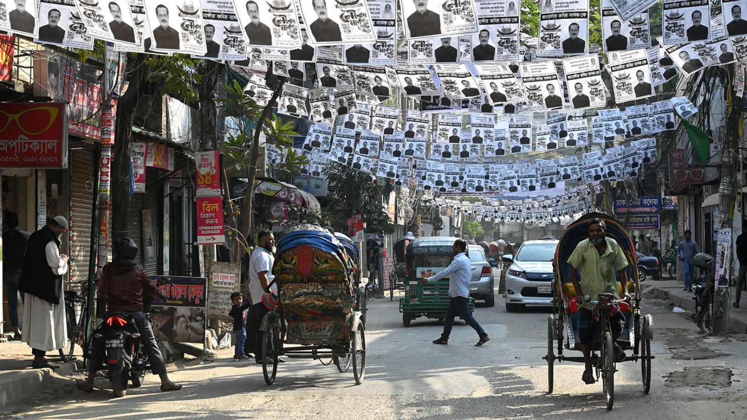 A Bangladeshi citizen is walking under posters of the ruling Bangladesh Awami League election candidates that are hanging over a street during the general election campaign in Dhaka, Bangladesh, on December 20, 2023.