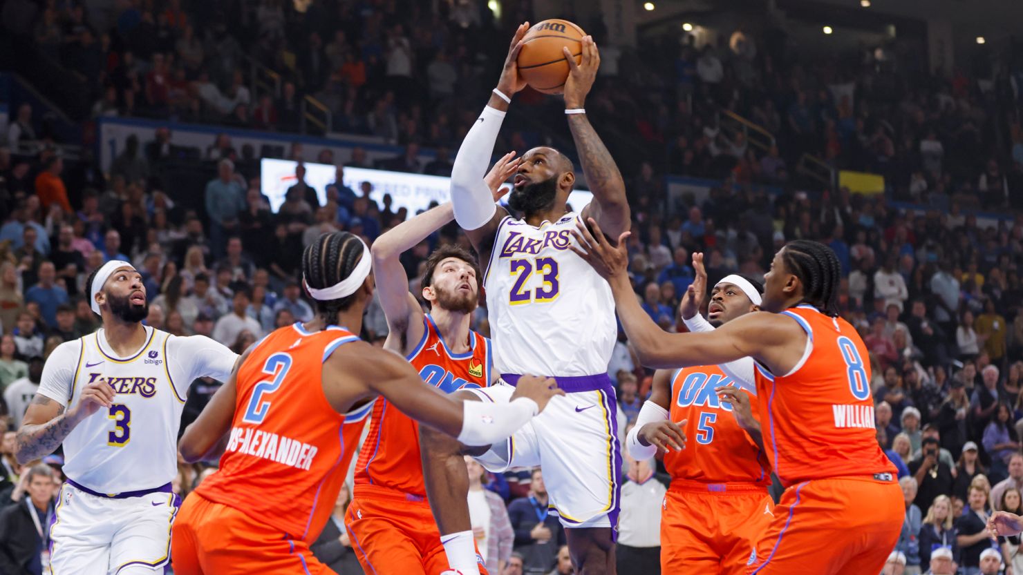 Los Angeles Lakers forward LeBron James (23) prepares to shoot between Oklahoma City Thunder guard Shai Gilgeous-Alexander (2), forward Chet Holmgren, third from left, guard Luguentz Dort (5) and forward Jalen Williams (8) as Lakers forward Anthony Davis (3) watches during the first half of an NBA basketball game Saturday, Dec. 23, 2023, in Oklahoma City. (AP Photo/Nate Billings)