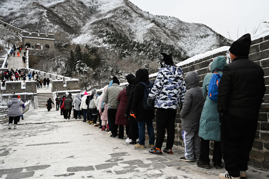 People hold a rope as they climb down an icy section of the Great Wall of China at Badaling, north of Beijing, after an overnight snowfall on December 15, 2023.