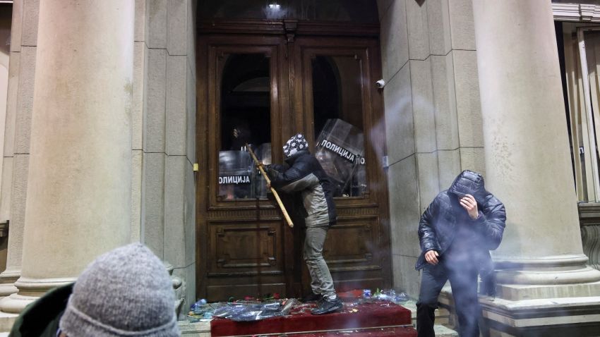 Police officers cover the door of the city hall as a protester uses a stick to hit them during a protest by supporters of the opposition 'Serbia Against Violence' (SPN), after the SPN alleged major election law violations in the Belgrade city and parliament races, in Belgrade, Serbia, December 24, 2023. REUTERS/Zorana Jevtic