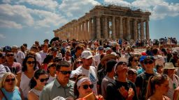 Atop the Acropolis ancient hill, tourists visit the Parthenon temple, background, in Athens, Greece, Tuesday, July 4, 2023.